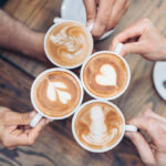 Above view of hands holding cappuccino cups